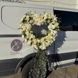 Heart-shaped white floral wreath on a stand