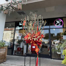 Tall red and gold floral display with pussy willow branches and hanging ornaments