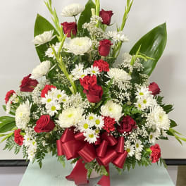 Red roses and white daisies in a vase with a red ribbon