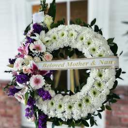 White and purple funeral wreath with a ribbon reading Beloved Mother & Nana