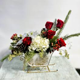 Red roses and white hydrangea in a decorative sleigh container