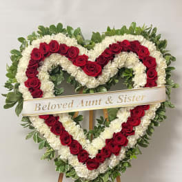 Heart-shaped funeral wreath of red roses and white carnations on an easel