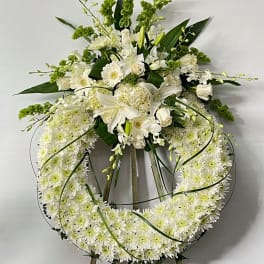 White floral funeral wreath on an easel with lilies and chrysanthemums