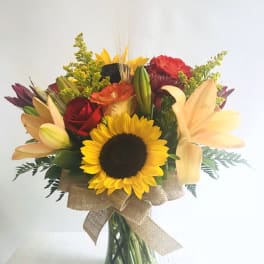 Mixed bouquet with a sunflower, lilies, and roses in a glass vase