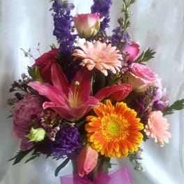 Mixed bouquet in a glass vase with pink, orange, and purple flowers