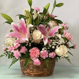 Pink lilies and roses arranged in a wicker basket