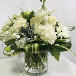 White floral arrangement in a clear glass vase with a striped leaf wrap