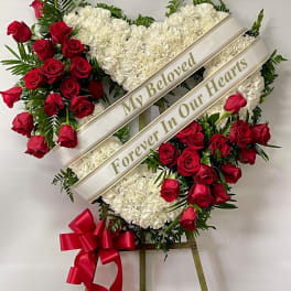 Heart-shaped funeral wreath with red roses and white carnations on an easel