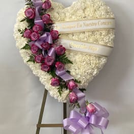 Heart-shaped white floral tribute with pink roses and lavender ribbon
