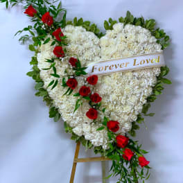Heart-shaped white floral spray with red roses and a "Forever Loved" ribbon