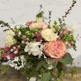 Mixed bouquet of pink, cream, and white flowers in a glass vase