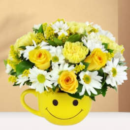 Yellow and white flower arrangement in a smiley-face mug