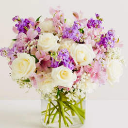 Pink and purple bouquet with white roses in a clear glass vase