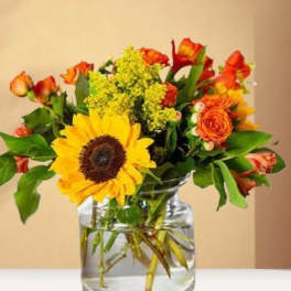 Sunflower and orange rose bouquet in a clear glass vase