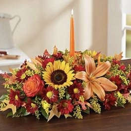 Autumn floral centerpiece with a sunflower and orange lily around a candle