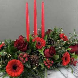 Low floral centerpiece with red roses, red gerbera daisies, and tall red candles