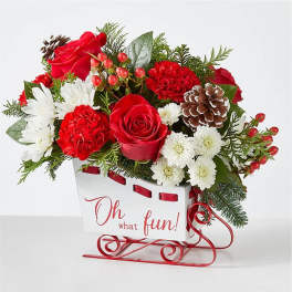 Red and white floral arrangement in a sleigh-shaped container