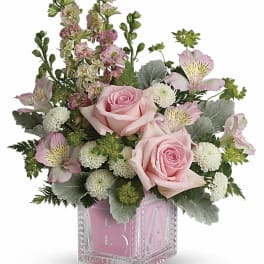 Pink roses and mixed blooms arranged in a clear pink glass vase