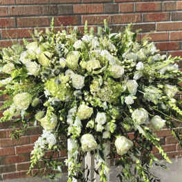 Large white floral arrangement with roses and trailing greenery