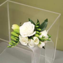 White floral wrist corsage with green buds and ribbon