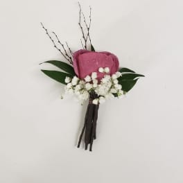 Pink rose boutonniere with white baby's breath and dark leaves