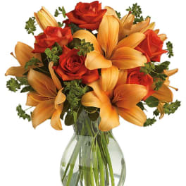 Orange lilies and red roses in a clear glass vase