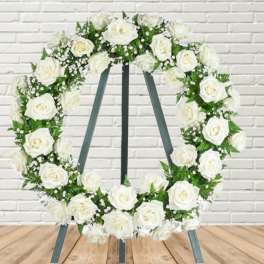 White rose wreath on a standing easel with dark ribbon