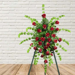 Standing floral spray of red roses with trailing green foliage on an easel