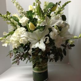 White lilies and tulips arranged in a glass vase