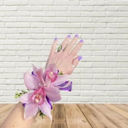 Pink orchid corsage on a wrist with purple ribbon