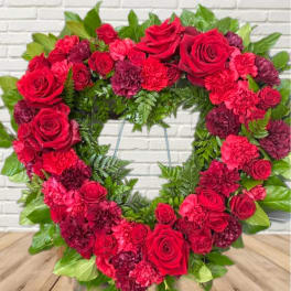 Heart-shaped wreath of red roses and carnations with green foliage
