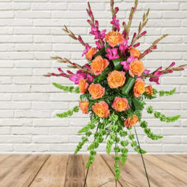 Orange roses and magenta flowers in a tall standing arrangement