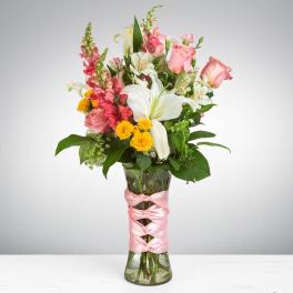 Pink and white mixed bouquet in a glass vase with a pink ribbon