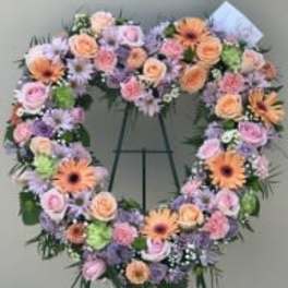 Heart-shaped floral wreath on a standing easel with pastel blooms