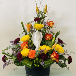 Colorful floral arrangement with roses, lilies, and a white angel figurine in a black container