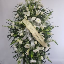 Large white funeral spray with lilies, roses, and a ribbon