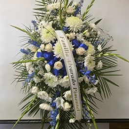 Standing funeral spray of white and blue flowers with a ribbon tribute