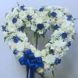 Heart-shaped white floral wreath with blue roses and a blue ribbon bow