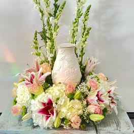 Tall floral arrangement with lilies, roses, hydrangeas, and a white vase