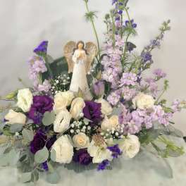 Purple and white floral arrangement with an angel figurine
