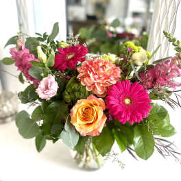 Mixed bouquet of pink and orange flowers in a glass vase