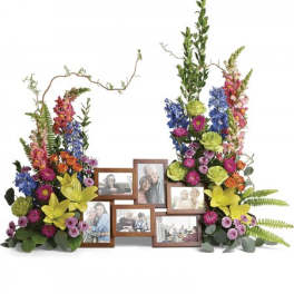 Colorful twin floral sprays with lilies and mixed blooms surrounding a wooden multi-photo frame