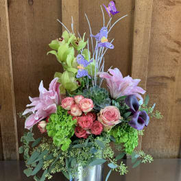 Mixed floral arrangement in a metal vase with pink roses and lilies