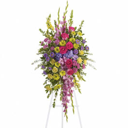 Tall standing floral spray with pink, purple, and yellow flowers on an easel