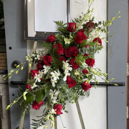 Standing floral spray with red roses and white orchids on an easel