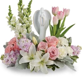 Pink and white floral arrangement with an angel figurine