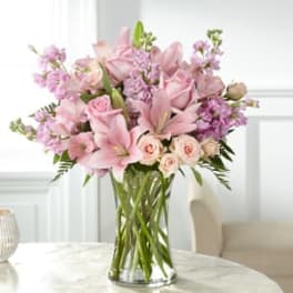 Pink lilies and roses arranged in a clear glass vase