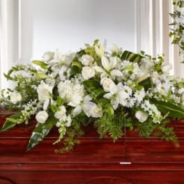 White floral casket spray with lilies and roses