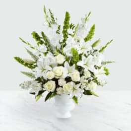 White lilies and roses in a white vase with green accents