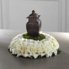 White floral wreath with a dark urn centerpiece